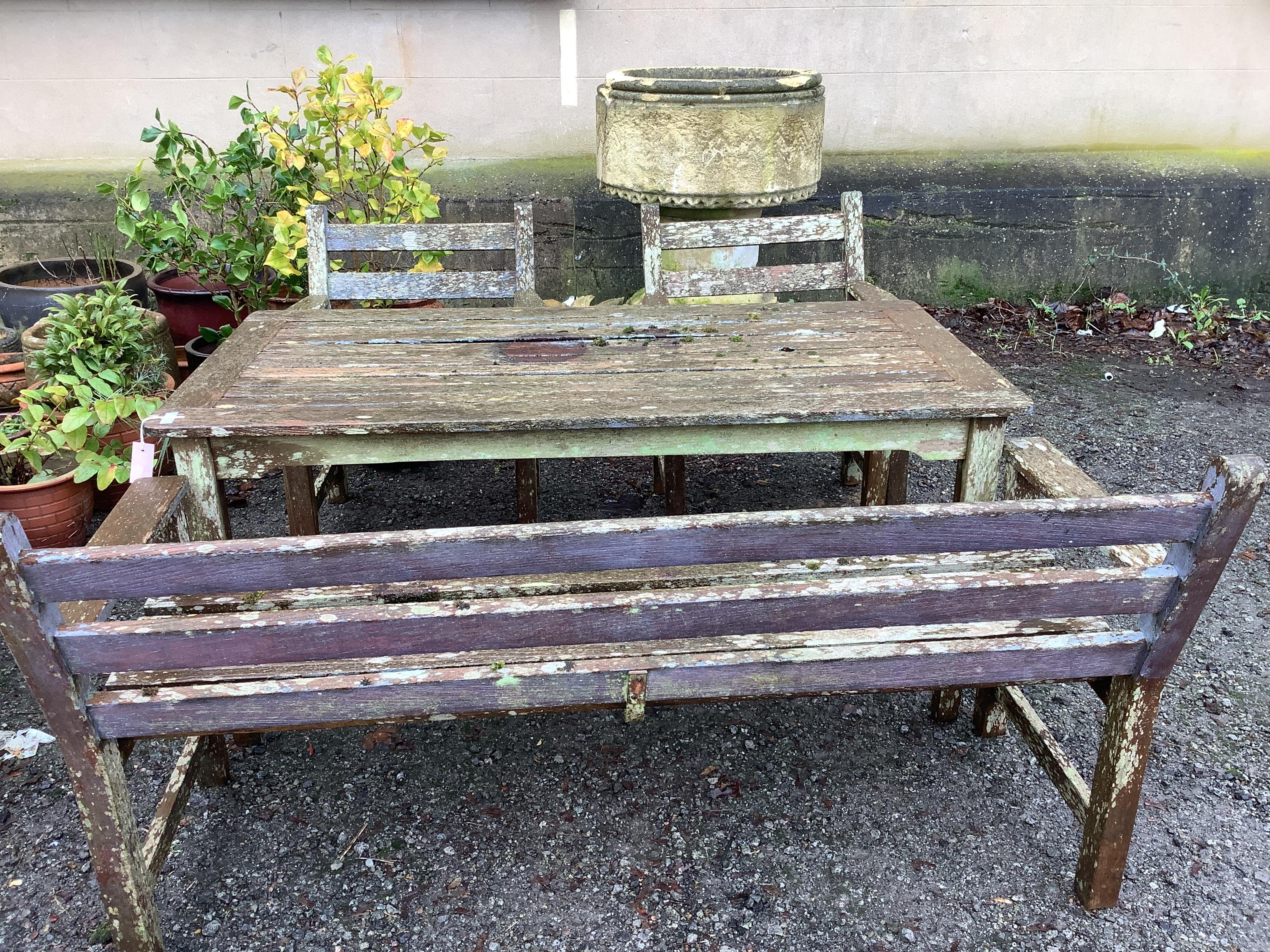 A rectangular teak garden table, width 152cm, depth 77cm, height 68cm, together with a slatted teak garden bench and two armchairs